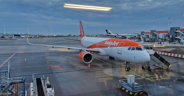An easyJet plane parked at an airport gate on a wet, grey day.
