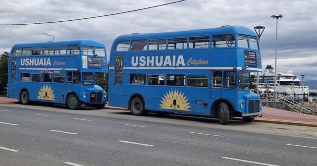 Two blue double-decker sightseeing buses labelled Ushuaia parked by the roadside.