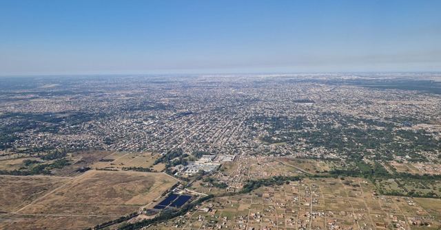 Aerial view of a vast sprawling city grid and green land stretching to the horizon.