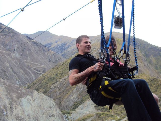 A man in a harness swinging over a steep canyon on the Nevis Swing.