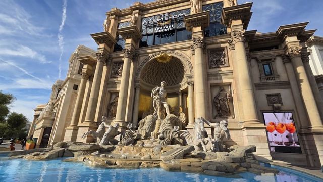 Ornate Roman-style fountain with marble statues in front of a grand columned facade in Las Vegas.