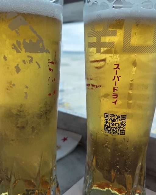 Two tall glasses of cold lager with Japanese lettering on the glass.