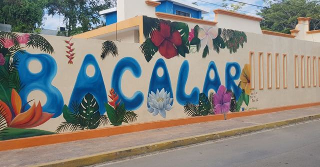 A colourful painted wall spelling Bacalar decorated with tropical flowers and birds.