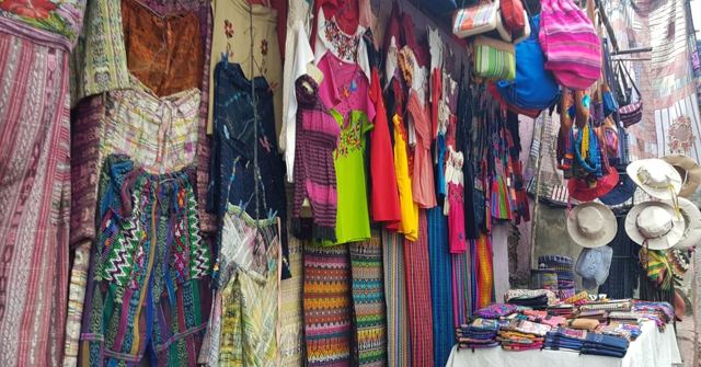 A market stall hung with brightly coloured woven Guatemalan textiles and bags.