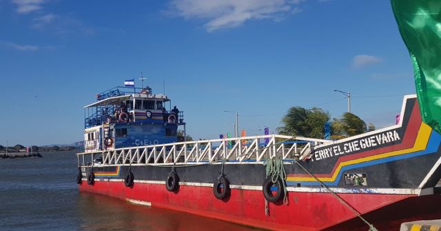 A red and white passenger ferry moored on a lake under blue sky.