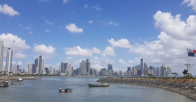 The Panama City skyline of tall towers across a bay with small boats in the foreground.
