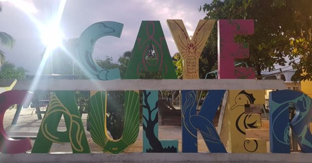 Large colourful Caye Caulker letters with bright sunlight bursting through behind them.
