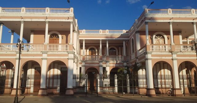 A two-storey colonial building with arches and balconies in warm light.