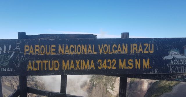 A dark sign reading Parque Nacional Volcan Irazu, altitude 3432 metres, against blue sky.