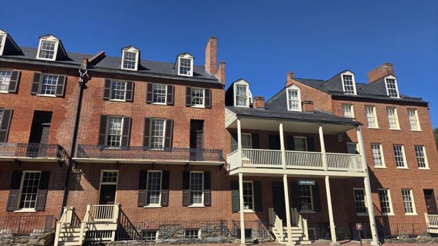 Historic red-brick buildings with white porches and balconies under a blue sky.