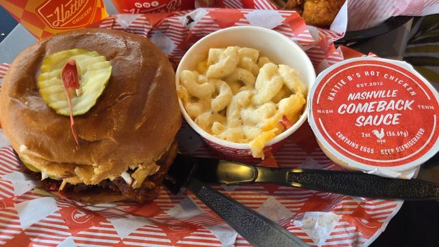 A chicken sandwich with pickle, a bowl of mac and cheese and a pot of Nashville Comeback Sauce.