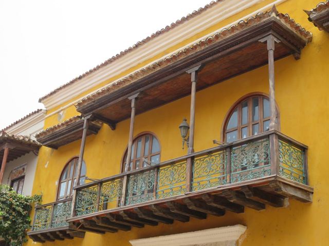 A bright yellow colonial house with a carved wooden balcony in Cartagena's old town