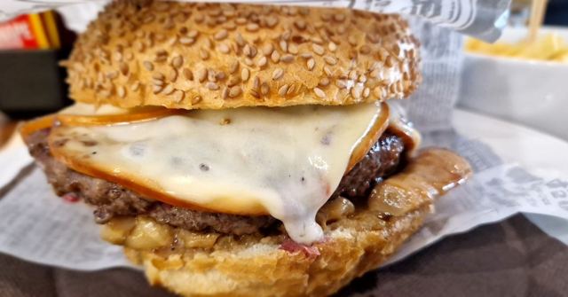 Close-up of a cheeseburger with a sesame seed bun and melting cheese.