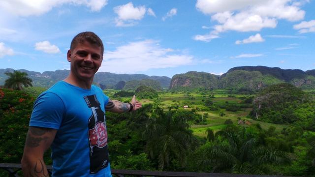 A man pointing out over the green Viñales Valley and its rounded limestone hills.