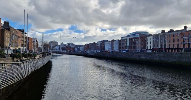 The River Liffey flowing between quays lined with colourful terraced buildings under a cloudy sky.