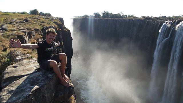 A man sitting on a rock at the edge of the gorge opposite Victoria Falls.