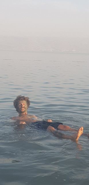 A man floating on his back in the calm, hazy water of the Dead Sea.
