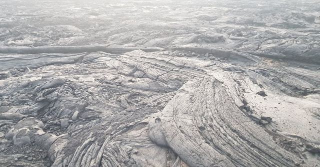 A wide field of grey solidified lava with swirling flow patterns.