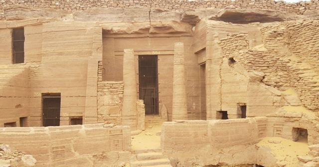 Ancient rock-cut tomb entrances carved into a sandstone cliff face.
