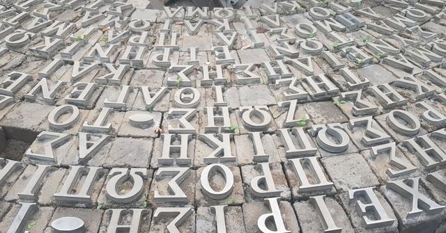 Large stone Greek letters laid closely together across the ground.