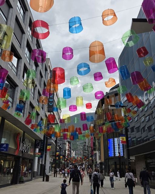 Pedestrian shopping street with colourful translucent lampshades hanging overhead.