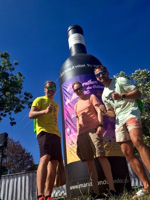 Two runners posing in front of a giant inflatable wine bottle.