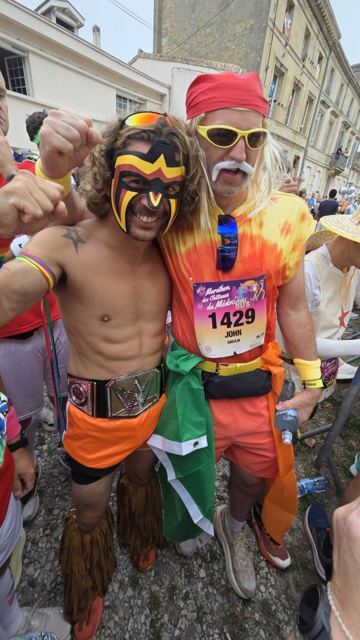 Two runners in face paint and costumes flexing in a crowd at the start.
