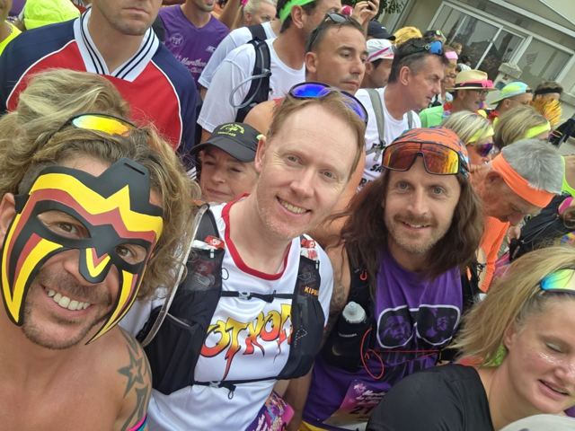 Runners in face paint and costumes taking a selfie in a crowded start pen.
