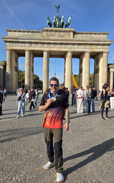 A man wearing a medal standing in front of the Brandenburg Gate.