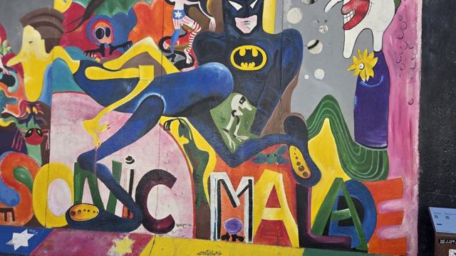 Bright graffiti mural with cartoon figures including Batman and bold colourful lettering.