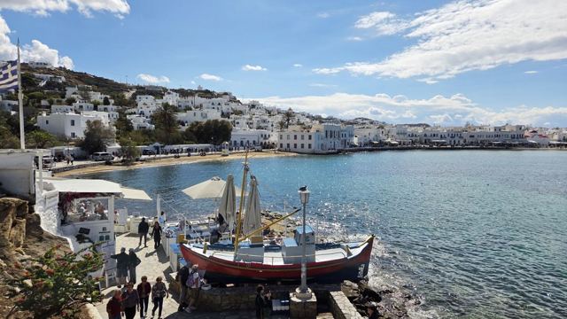 Harbour with a traditional fishing boat on the quay and white buildings across the bay.