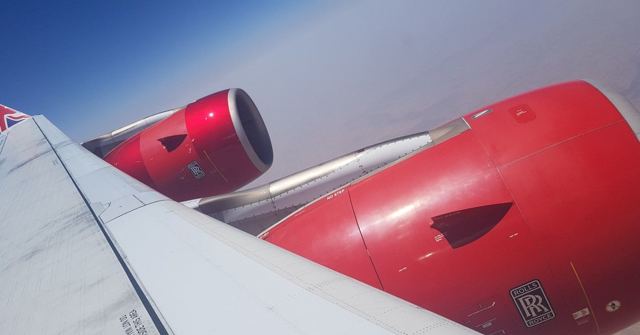 An aircraft wing with a red jet engine seen from a window seat.