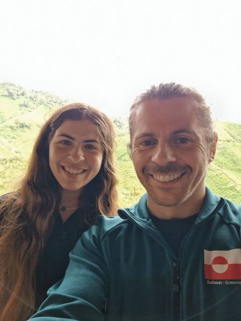 A smiling man and a woman taking a selfie on a misty hillside.
