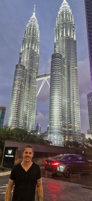 A man standing at the foot of the gleaming Petronas Twin Towers.