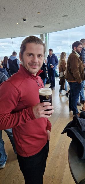 A man holding a pint of Guinness in the busy rooftop Gravity Bar.