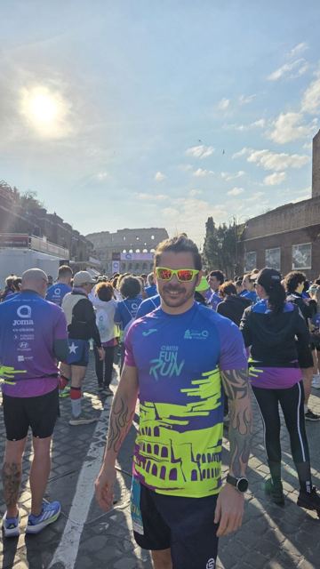 A man in sunglasses among runners at the start with the Colosseum in the background.