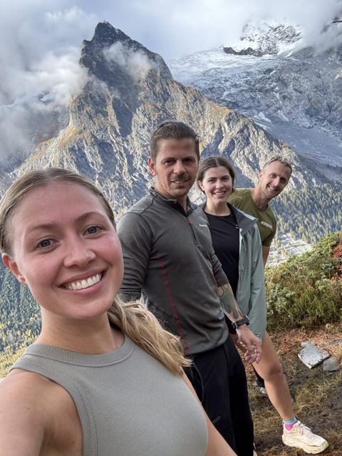 A group of friends taking a selfie with rugged snowy mountains behind.