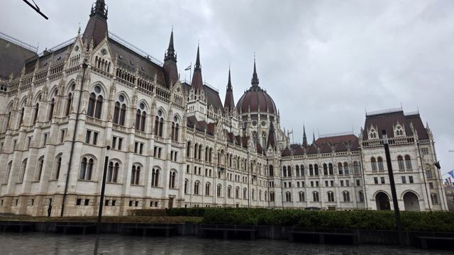 Ornate neo-Gothic parliament building with spires and domes under a cloudy sky.