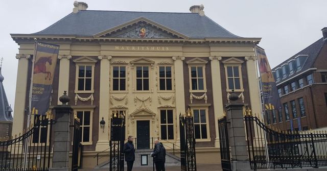 The classical facade of the Mauritshuis museum behind wrought-iron gates.