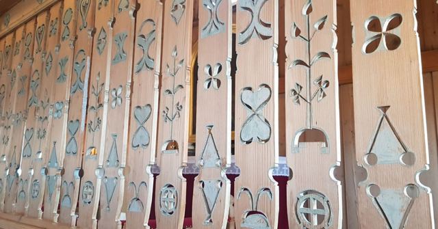 Rows of pale carved wooden panels with heart, clover and flower cut-outs.