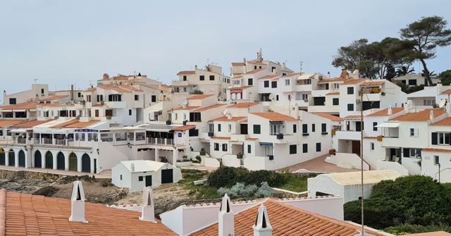 A hillside of whitewashed houses with terracotta roofs, seen from above.