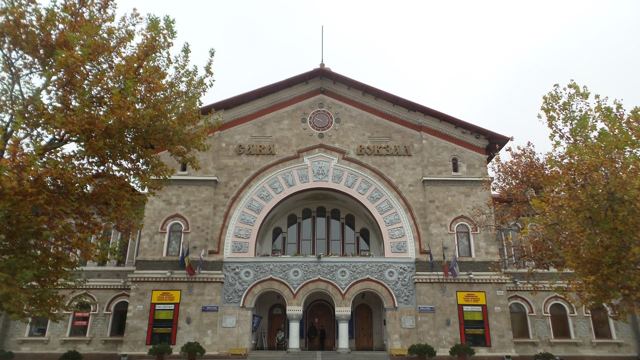 The arched facade of Chisinau railway station framed by autumn trees.