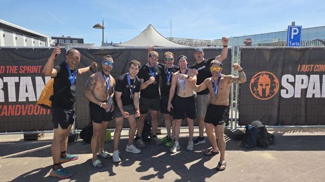 A group of racers flexing in front of a Spartan race banner.