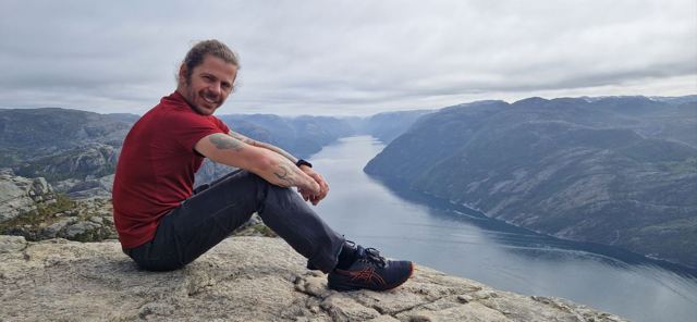 A man sitting on the edge of Pulpit Rock above a deep fjord.