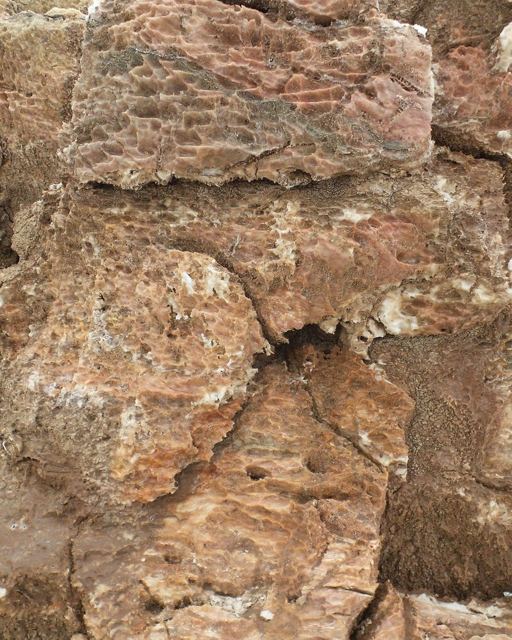 Close-up of cracked pink and rust-coloured salt crust.