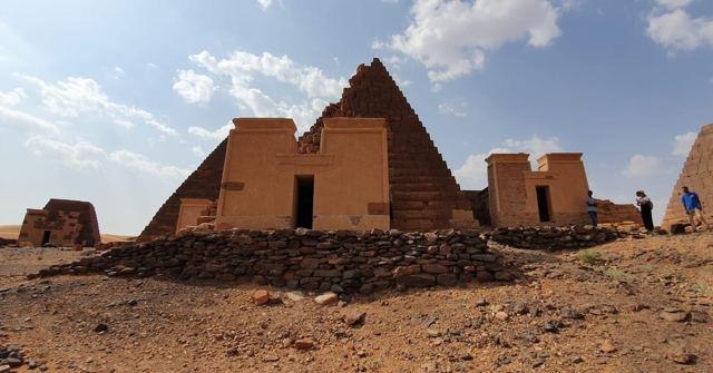 A steep pyramid with a temple-like chapel entrance in front, under a blue sky.