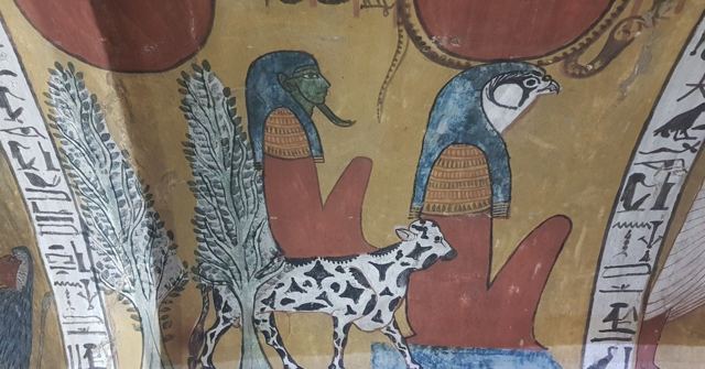 Vivid tomb painting with falcon-headed figures, palm trees and a spotted animal on a curved ceiling.