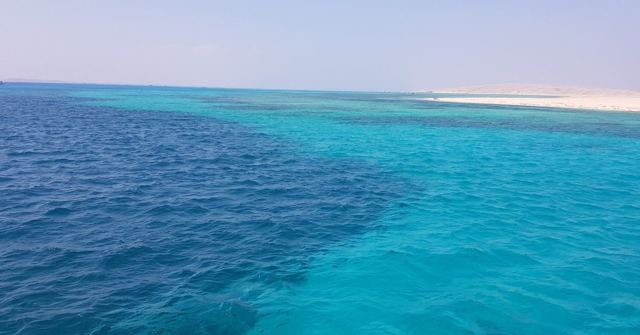 Turquoise and deep blue Red Sea water stretching to a pale sandy shoreline.