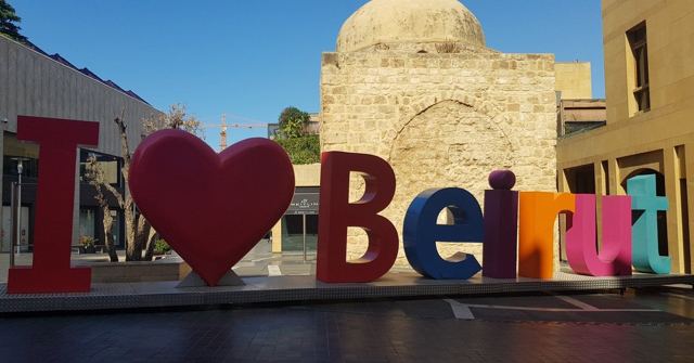 Colourful I love Beirut letters in front of an old stone building with a dome.