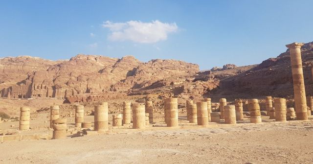 Remains of a colonnaded street with stone columns in front of sandstone mountains at Petra.